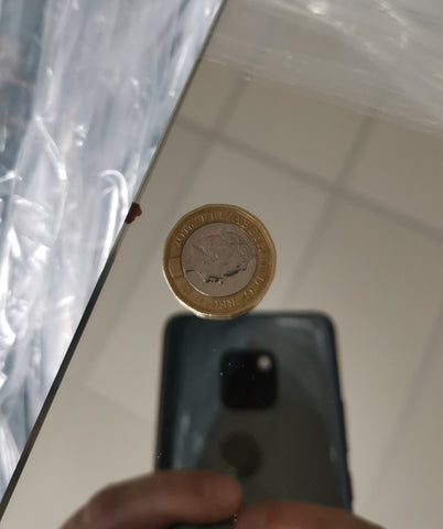 £1 coin next to brown mirror blemish